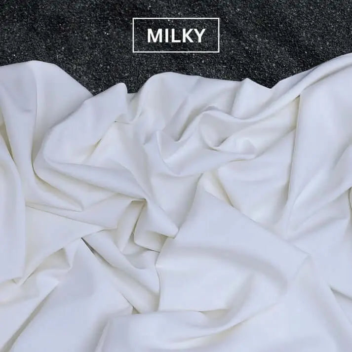 Soft milky white fabric draped on dark textured surface with MILKY label above